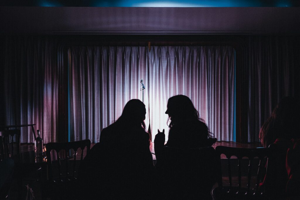a couple of women sitting next to each other in front of a window