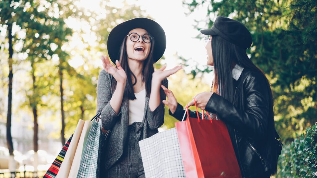 Two women with shopping bags in a park