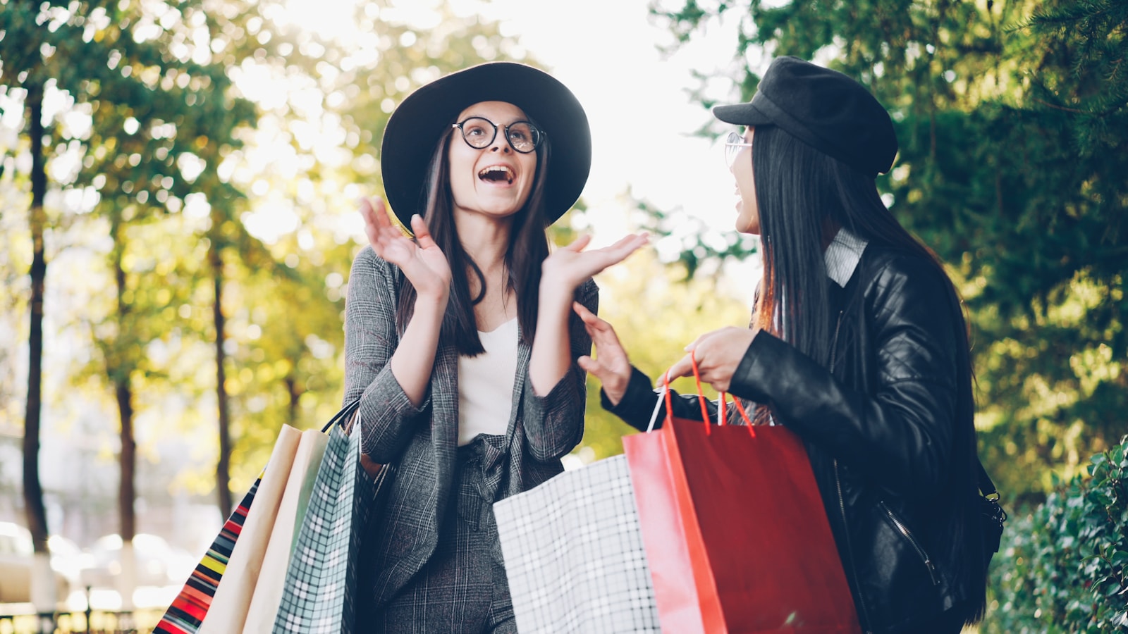 Two women with shopping bags in a park
